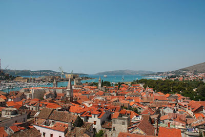 High angle view of houses by sea against clear blue sky