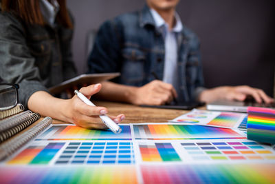 Midsection of woman holding hands while sitting on table