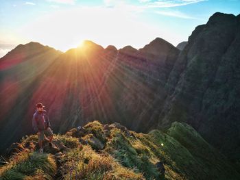 Full length of male hiker standing on top of mountain during sunset