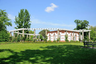 Built structure on field by trees against sky