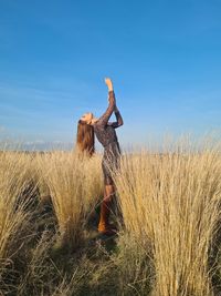 Woman standing on field against sky
