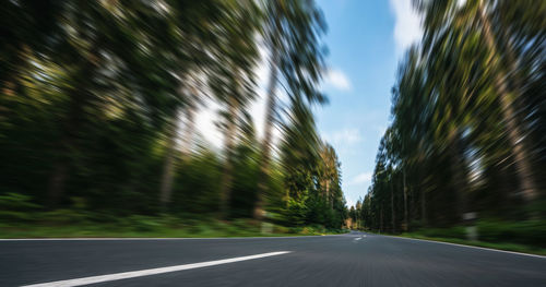 Empty road amidst trees against sky