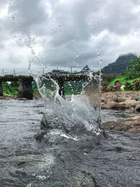 Water splashing in sea against sky during rainy season