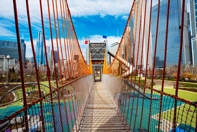 Footbridge amidst buildings in city against sky