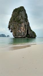 Rock formation on beach against sky