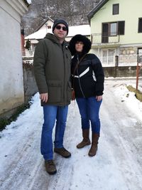 Full length of friends standing on snow covered building