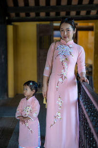 Portrait of woman standing with daughter indoors