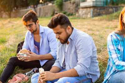 Friends eating food sitting at park