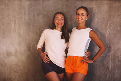 Portrait of smiling young woman standing against wall