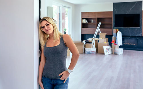 Portrait of smiling beautiful woman leaning on wall at home