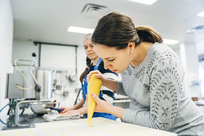 Chef filling molds while standing by coworker at chocolate factory