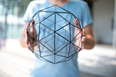 Coach in blue shirt holding mesh sphere