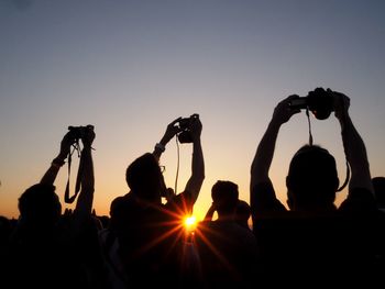 Silhouette people photographing at sunset