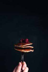 Hand holds a fork with juicy pancakes with berries and honey. high quality photo
