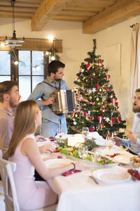 Young man playing accordion at christmas dinner table