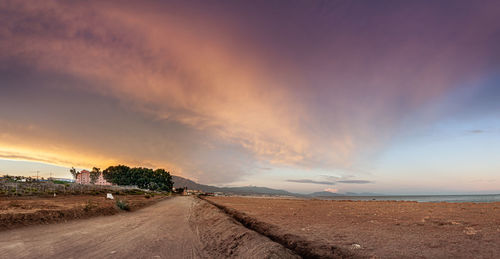 Road by land against sky during sunset