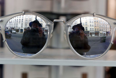 Mature man reflecting on sunglasses while photographing on city street