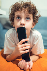 Boy watching tv holding the remote controller