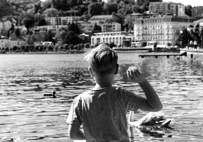 Rear view of boy standing by lake