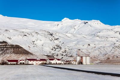 Road by snowcapped mountains against blue sky