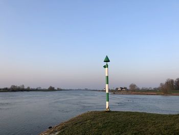 Lighthouse by lake against clear sky