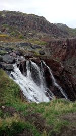 Scenic view of waterfall against sky