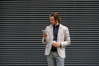 Focused man texting sms using app on smartphone during his break in the city