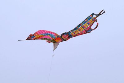 Low angle view of kites flying against clear sky