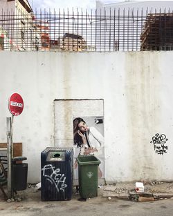 Full length of man standing on garbage bin against building