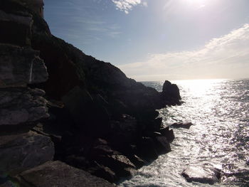 Rock formation on sea shore against sky