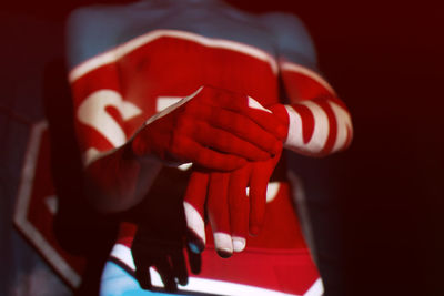 Midsection of man with text on hands and chest in darkroom