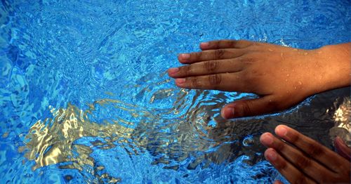 Close-up of hands on wet swimming pool