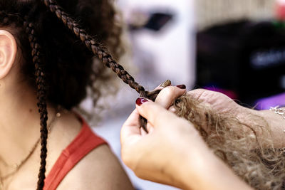 Hairdresser making braids to a young client at hairdresser salon