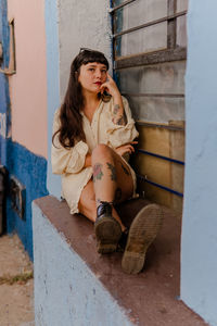 Dark-haired female model in vintage clothing and make-up against a colorful wall.