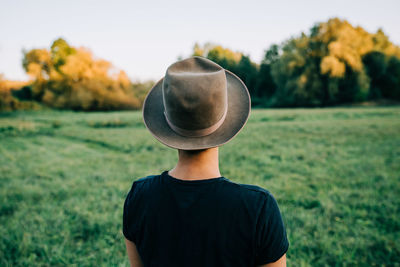 Rear view of teenage girl wearing hat against grassy field