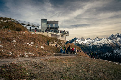 Group of people on snowcapped mountain against sky