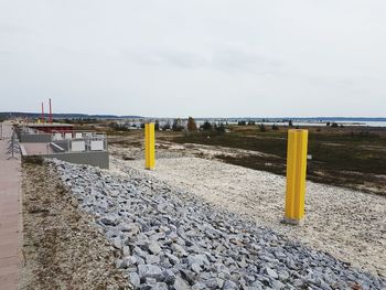 Yellow wooden posts on beach against sky