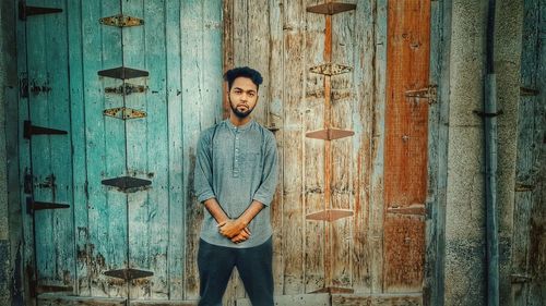 Portrait of young man standing against closed wooden door