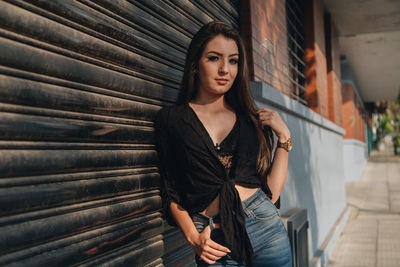 Portrait of woman standing by closed shutter