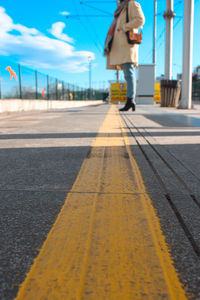 Lonely woman waiting behind the yellow line at the tram stop.