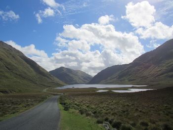 Scenic view of road by mountains against sky