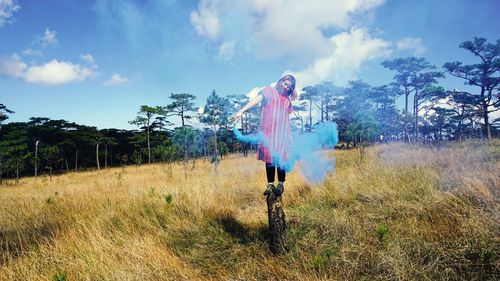 Woman with distress flare while standing on field against sky