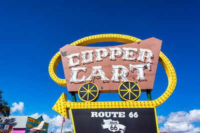 Low angle view of rollercoaster against clear blue sky
