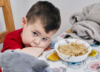 Expressive young boy waiting for his oatmeal to cool down