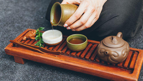 Cropped hand pouring tea in cup on table
