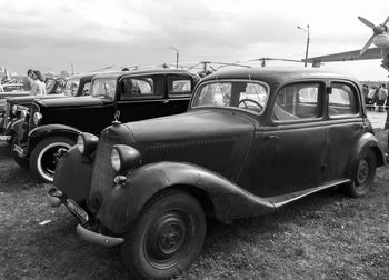 Cars parked on road against cloudy sky