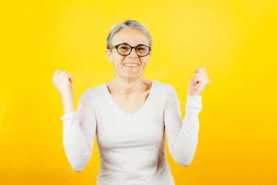 Portrait of young woman standing against yellow wall