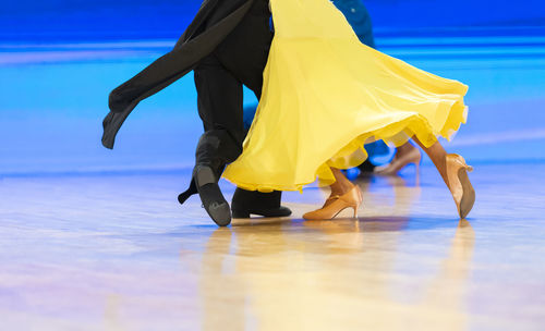 Low section of woman standing on yellow umbrella