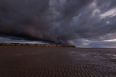 Scenic view of desert against cloudy sky