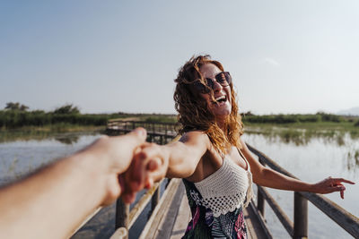 Young woman with umbrella in lake against sky